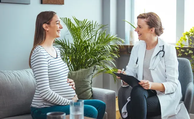 Women's health nurse practitioner smiling with pregnant patient